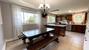 A kitchen with a large island, wooden cabinets, a chandelier, and a television.