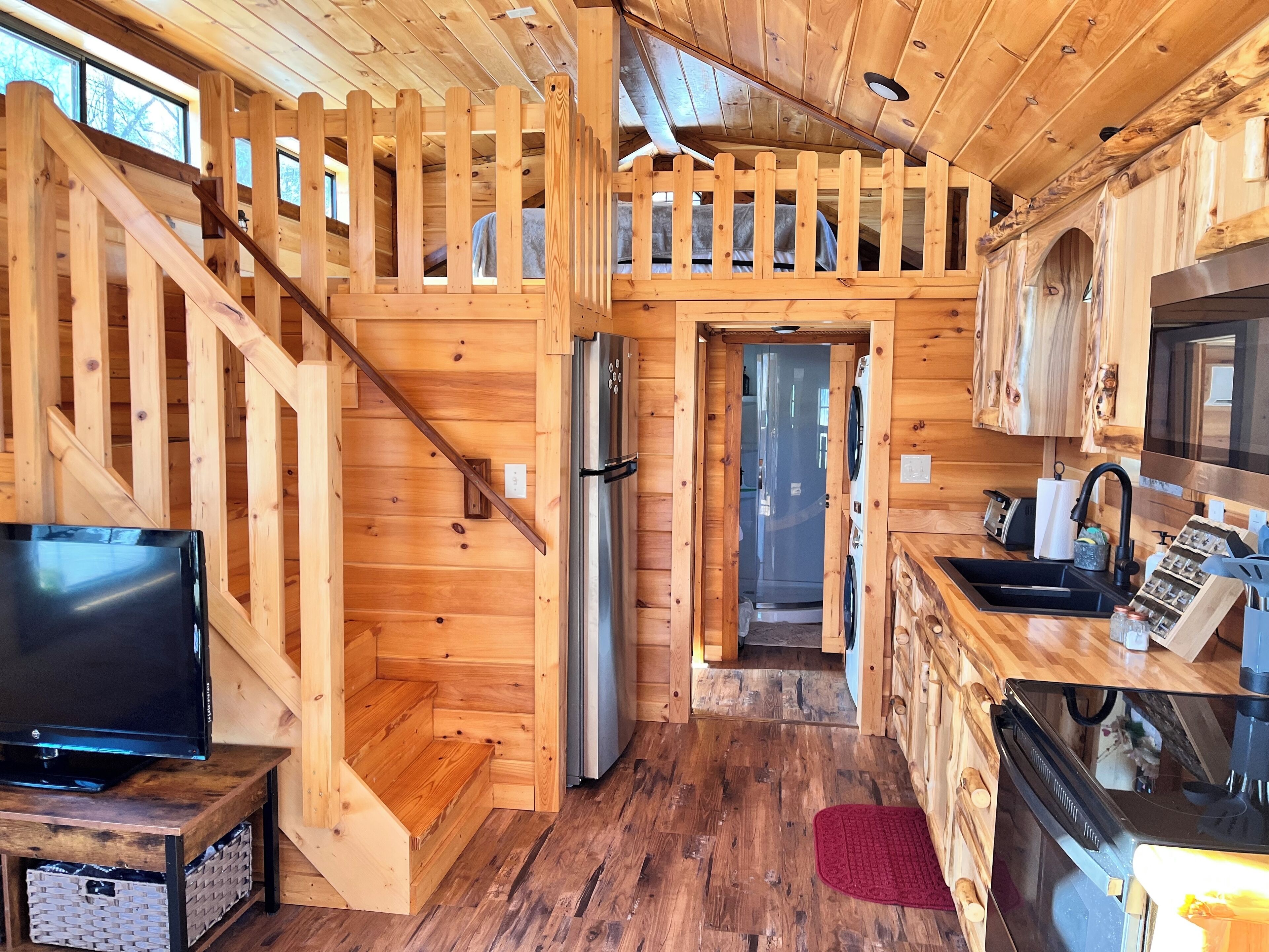 A wooden cabin interior with a kitchen, a dining area, and a living room.