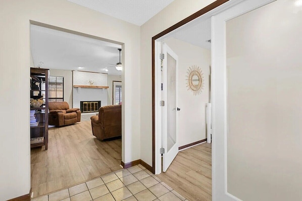 A spacious living room with a fireplace, a brown leather sofa, and a dining area with a chandelier.