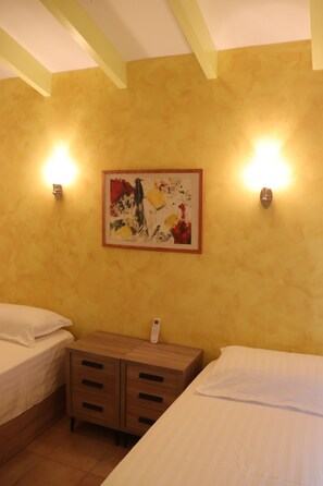 A hotel room with two beds, a wooden nightstand, and a painting on the wall. - VILLA LUCYA (El Campello)