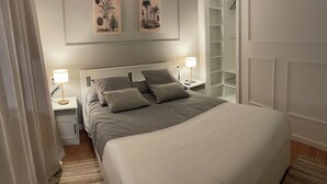 A neatly arranged bedroom with a large bed, two bedside tables with lamps, a wardrobe, and a framed artwork on the wall. - D'Moda lodging. Bright apartment in the center of Ribadeo. (Ribadeo)