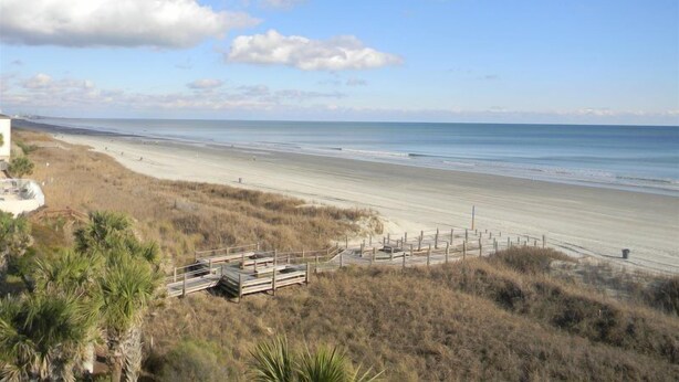 A beach with a wooden boardwalk leading to the shore, a sandy beach, and a clear sky. - Oceanfront Three Bedroom Condo - Crescent Sands C-4-September discounted! (North Myrtle Beach)