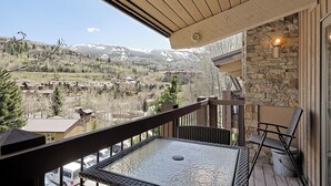 A balcony with a table and chairs, overlooking a mountainous landscape with buildings in the distance. - Beautiful 2 Bedroom + Loft Located in Snowmass (Snowmass Village)