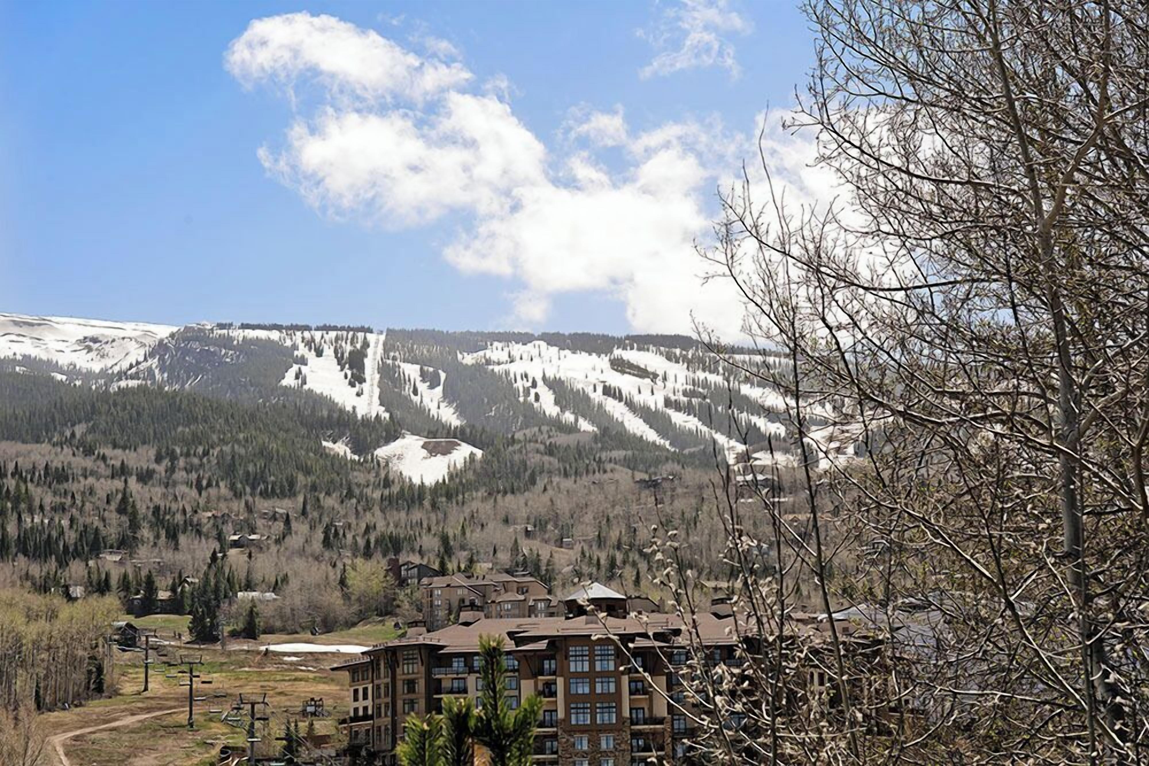 Une station de montagne avec des sommets enneigés, une piste de ski et un bâtiment à plusieurs étages.