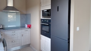 A kitchen with a black refrigerator, a microwave, and a stove. - We all want to go to the Ardèche! It's great! (Gras)