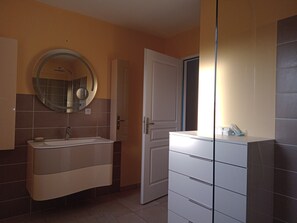 Une salle de bain avec un lavabo, un miroir et un meuble de rangement.