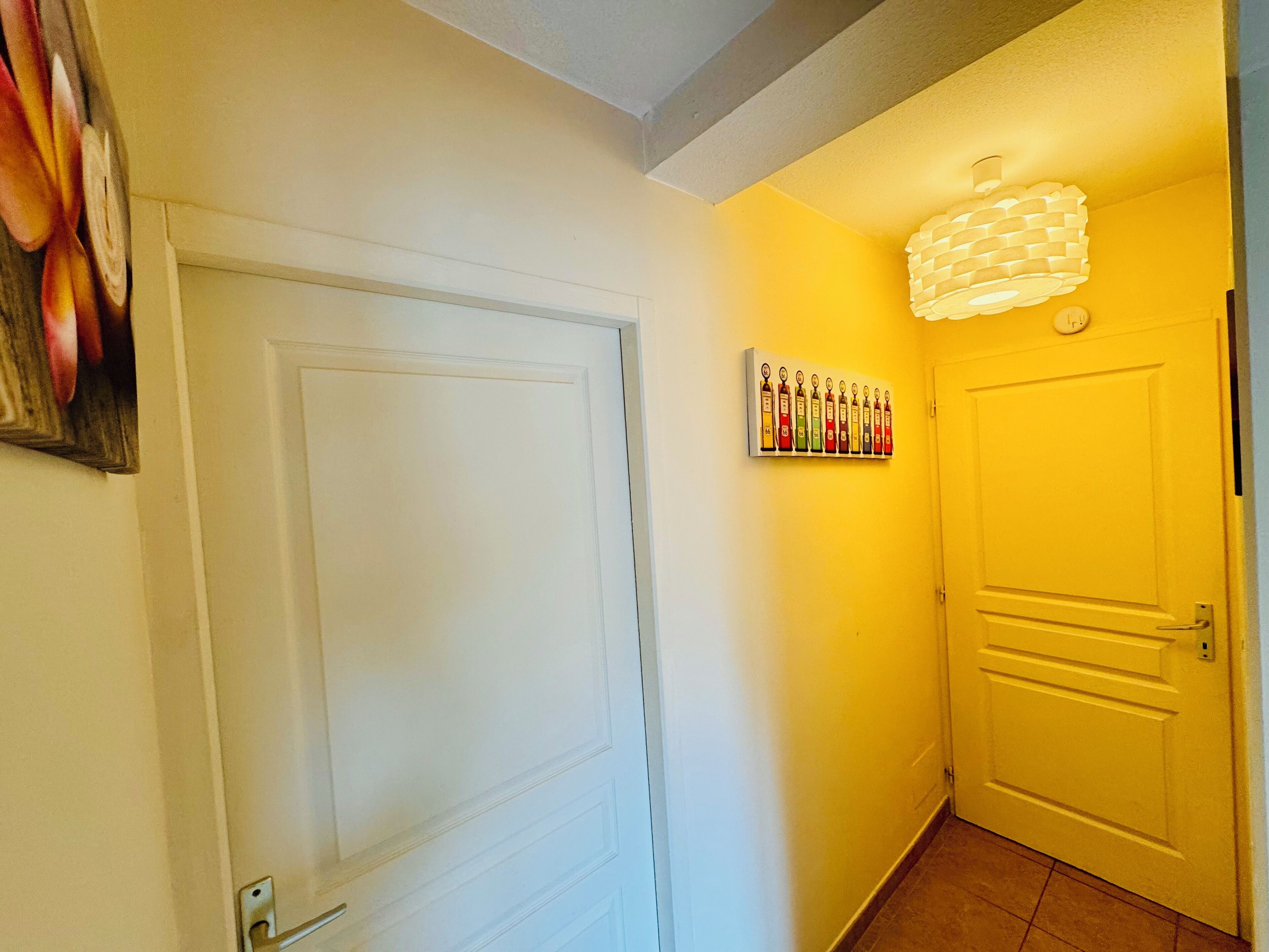 A hallway with a white door, a yellow wall, and a wall-mounted light fixture.