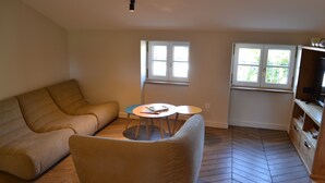 Una sala de estar con un sofá, una mesita y un mueble para televisión.