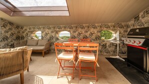 Un patio con mesa y sillas, una parrilla y un sofá.