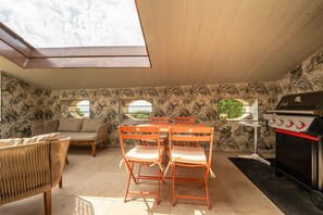 A patio area with a table and chairs, a grill, and a sofa.