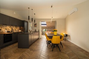 A modern kitchen with a central island, dark cabinetry, and a herringbone wood floor. - Air-conditioned apartment with a terrace in the center of Grimaud, 5 minutes from the ocean. (Grimaud)