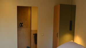 Habitación de hotel con dos camas, un armario de madera y un espejo.
