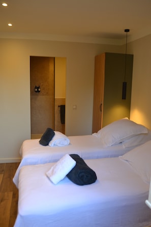 Ein Hotelzimmer mit zwei Betten, einem Holzschrank und einem Spiegel.