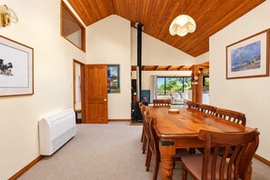 Un comedor con mesa y sillas de madera, un ventilador de techo y vistas al exterior.