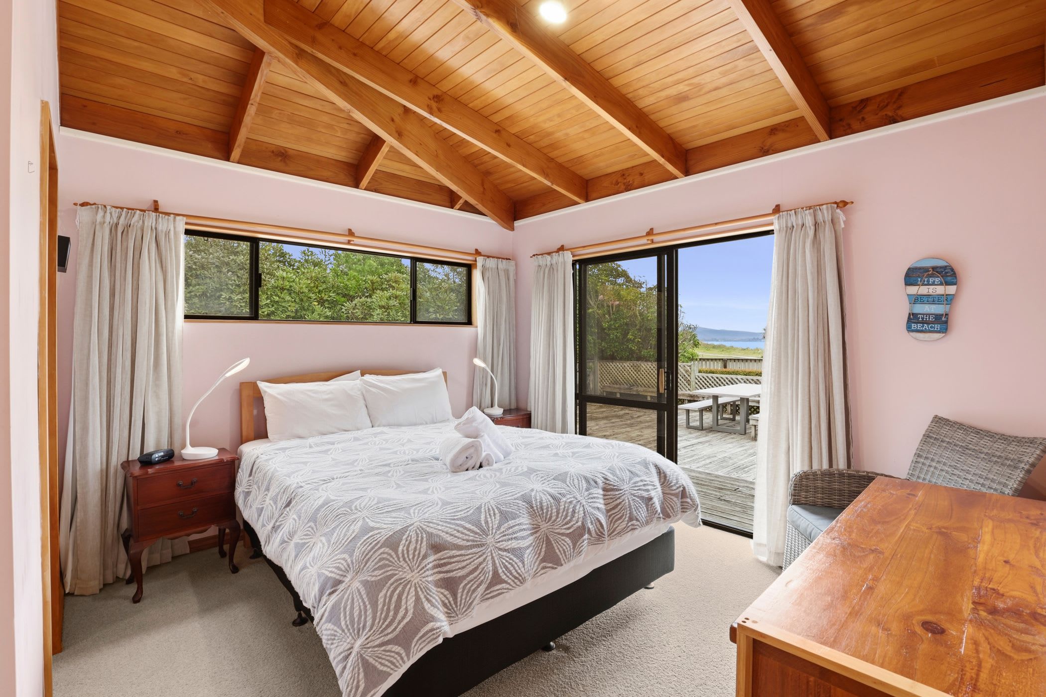 A bedroom with a bed, bedside tables, a desk, and a view of the outdoors.