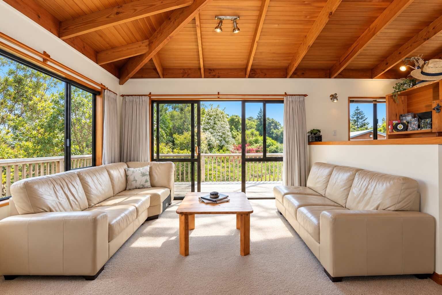 Amplia sala de estar con dos sofás de cuero, una mesa de centro de madera y ventanas grandes con vistas a zonas verdes.