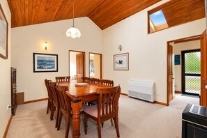 A dining room with a wooden table and chairs, a ceiling fan, and a window with a view.