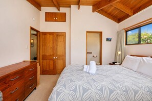 Un dormitorio con una cama grande, un armario de madera y un ventanal con vistas al verdor.
