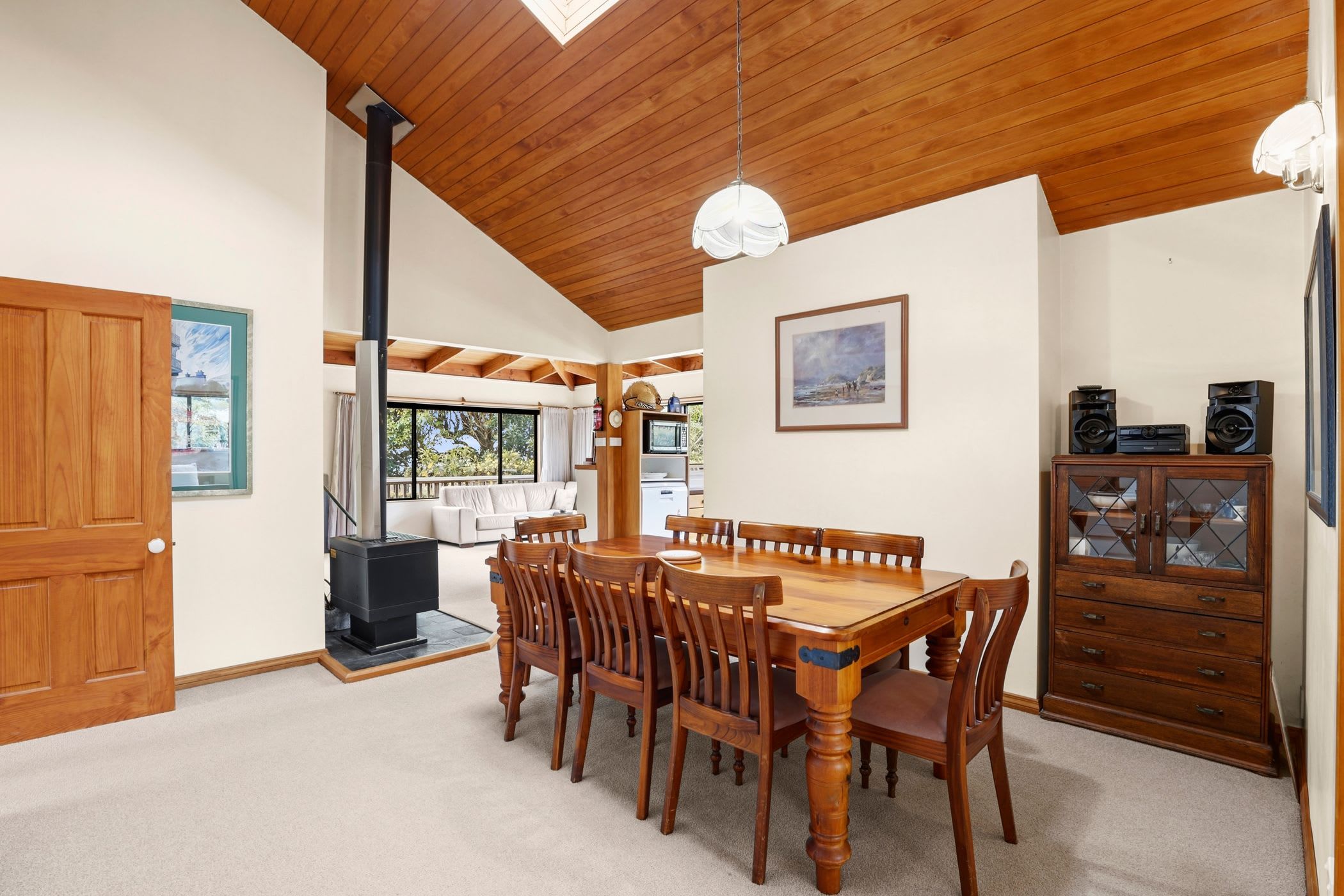 A dining area with a wooden table and chairs, a black stove, and a white ceiling.