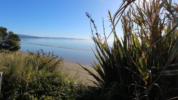 Een strand met heldere lucht en rustig water.