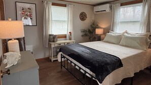 Una camera da letto con un letto, lampade da comodino, una scrivania, una sedia, un ventilatore a soffitto e un condizionatore d'aria.