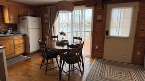 Un interno in legno con un tavolo da pranzo, sedie, un frigorifero e una finestra con persiane.
