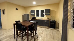 A compact kitchen with a dining area, featuring a refrigerator, microwave, stove, and cabinets. - ZEMMA Apartments Unit 2 (Willemstad)