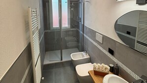 A modern bathroom with a glass-enclosed shower, a toilet, a sink, and a mirror.