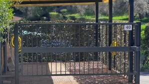 A gated entrance with a canopy, a number sign, and a paved area with a stone pattern.
