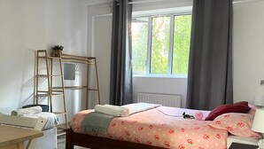 Un dormitorio con cama de madera, un escritorio, una escalera y una ventana con cortinas.