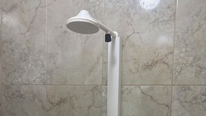 Een douche met een witte handdouche, bevestigd aan een verticale witte houder.