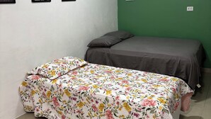 Een kleine kamer met een bed, een groene wand en drie ingelijste foto's aan de muur.