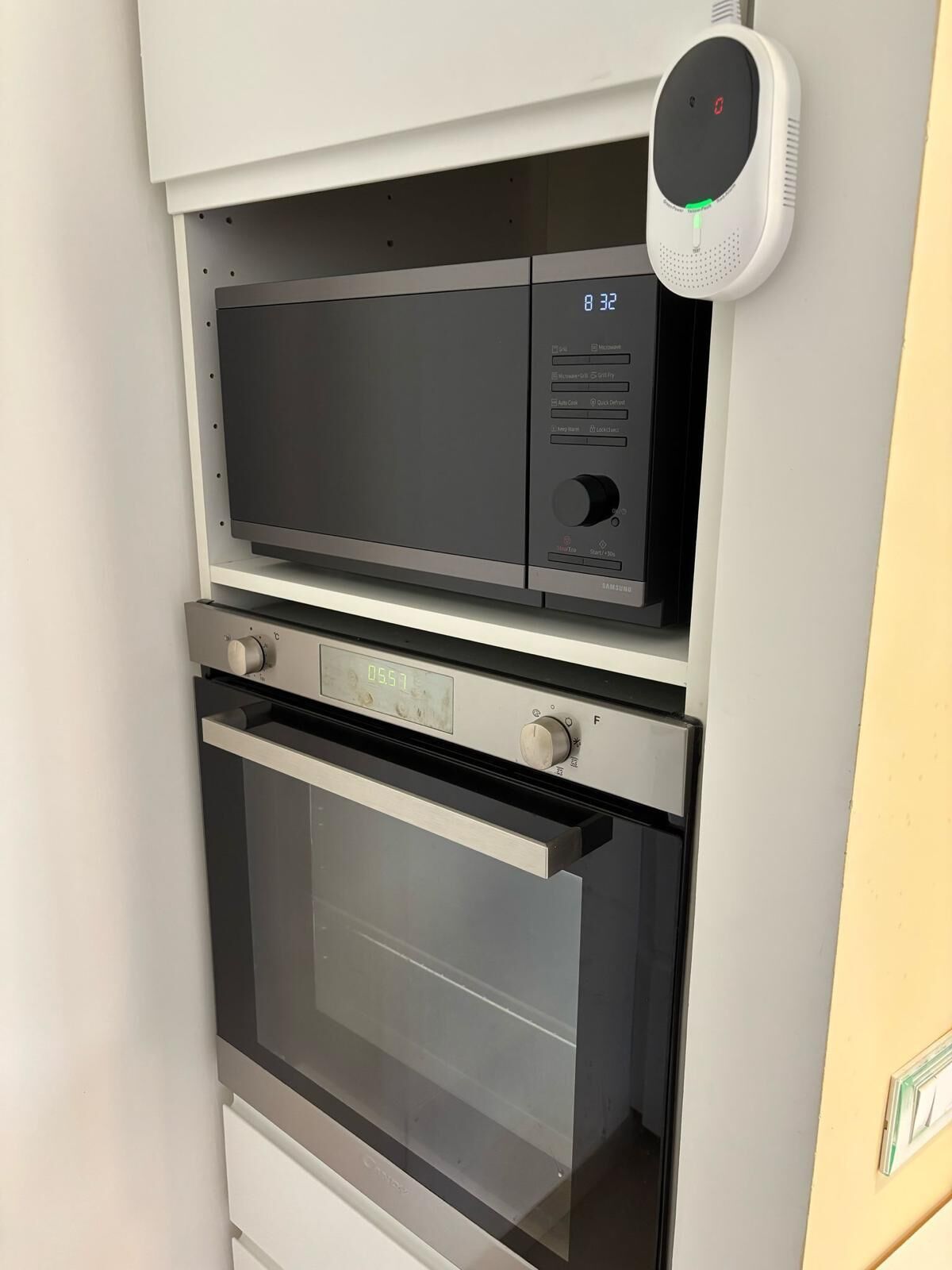 Une cuisine compacte dotée d’un four à micro-ondes et d’un four encastrés, d’une horloge numérique et d’un panneau de commande avec divers réglages.