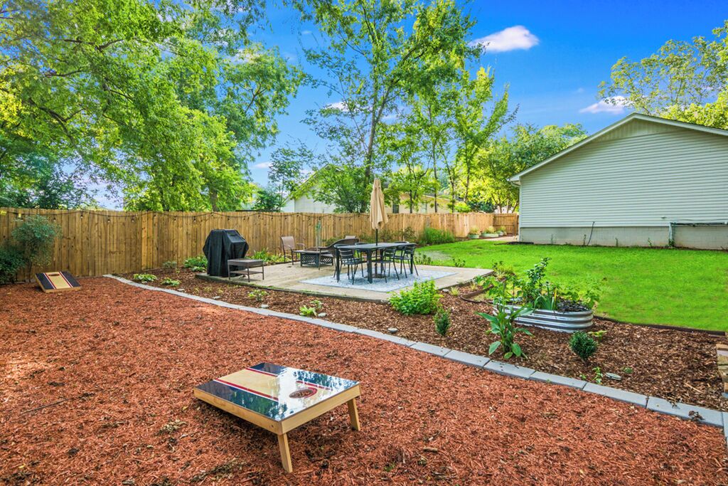 A backyard with a wooden deck, a barbecue grill, and a patio area.