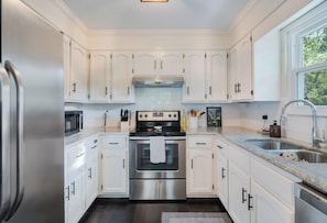 Una cocina moderna con armarios blancos, electrodomésticos de acero inoxidable y encimera de granito.