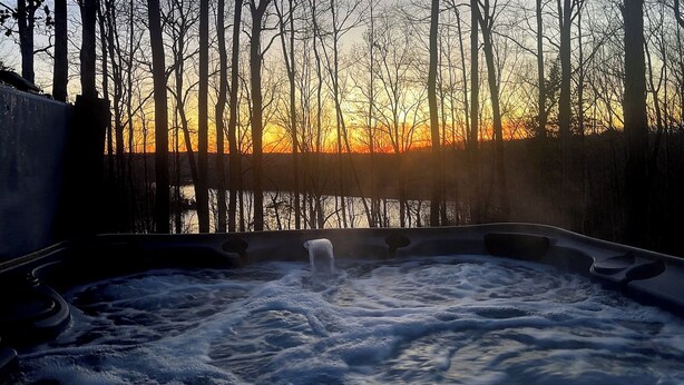 Ein Whirlpool, umgeben von Bäumen, mit Sonnenuntergang im Hintergrund.
