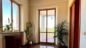A spacious hallway with a polished floor, a wooden cabinet, and potted plants.
