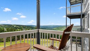 A balcony with a wooden chair and table, overlooking a scenic landscape. - ML244 Mountain View EZ Parking WiFi Near Village (Snowshoe)