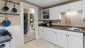 A kitchen with white cabinets, a microwave, a coffee maker, and a dish rack with plates. - Jasmine Cottage - Hot Tub - Very Pet Friendly (Wilmington)