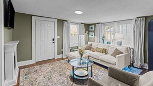 A living room with a sofa, a coffee table, a fireplace, and a television. - Jasmine Cottage - Hot Tub - Very Pet Friendly (Wilmington)