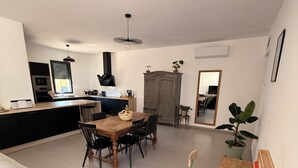 Une cuisine moderne avec un coin repas, un canapé en cuir noir et une table en bois avec des chaises.