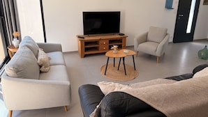 Un salon moderne avec un canapé, un fauteuil et un meuble pour la télévision.