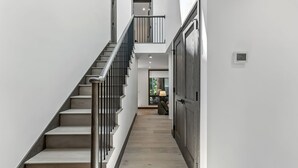 Un intérieur moderne avec un escalier menant à un deuxième étage, un plancher en bois et une porte sur le côté droit.