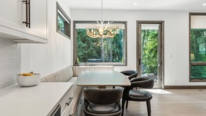 Une cuisine moderne dotée d’un grand îlot central, de chaises sombres et d’un lustre original.