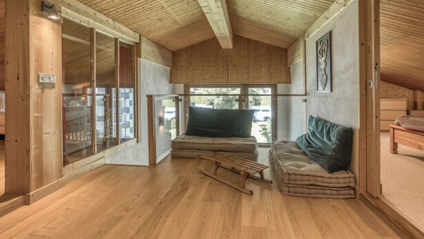 A cozy room with wooden walls and ceiling, a large window, a bed, a small table, and a chair. - Brévent Loft – Cozy 3-bedroom duplex, 250m to Planpraz cable car (Chamonix-Mont-Blanc)