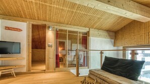 A wooden interior with a sofa, a television, and a wooden chair. - Brévent Loft – Cozy 3-bedroom duplex, 250m to Planpraz cable car (Chamonix-Mont-Blanc)
