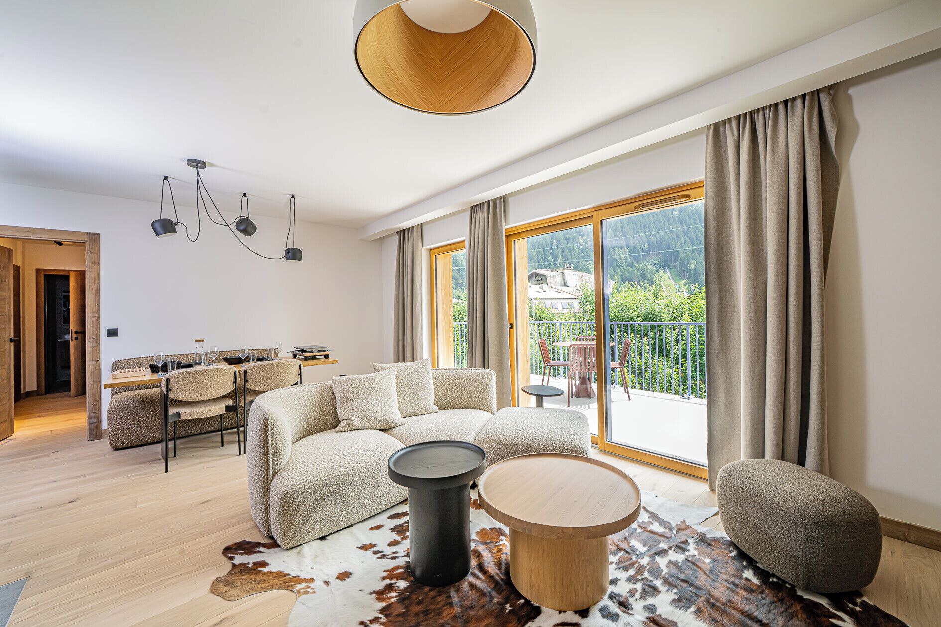 Un salon moderne comprenant un ensemble de canapés, une table basse ronde en bois et un coin repas avec une table et des chaises.