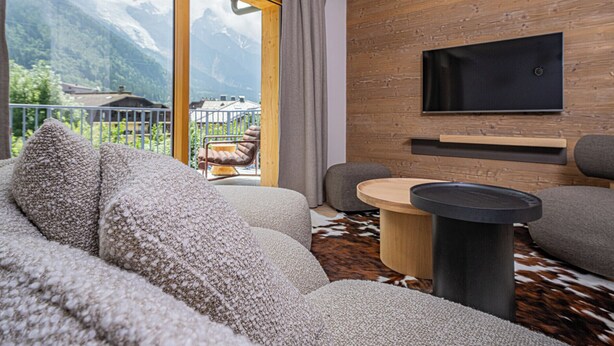 Een moderne woonkamer met een groot raam, een wandgemonteerde televisie en een gezellige zithoek.