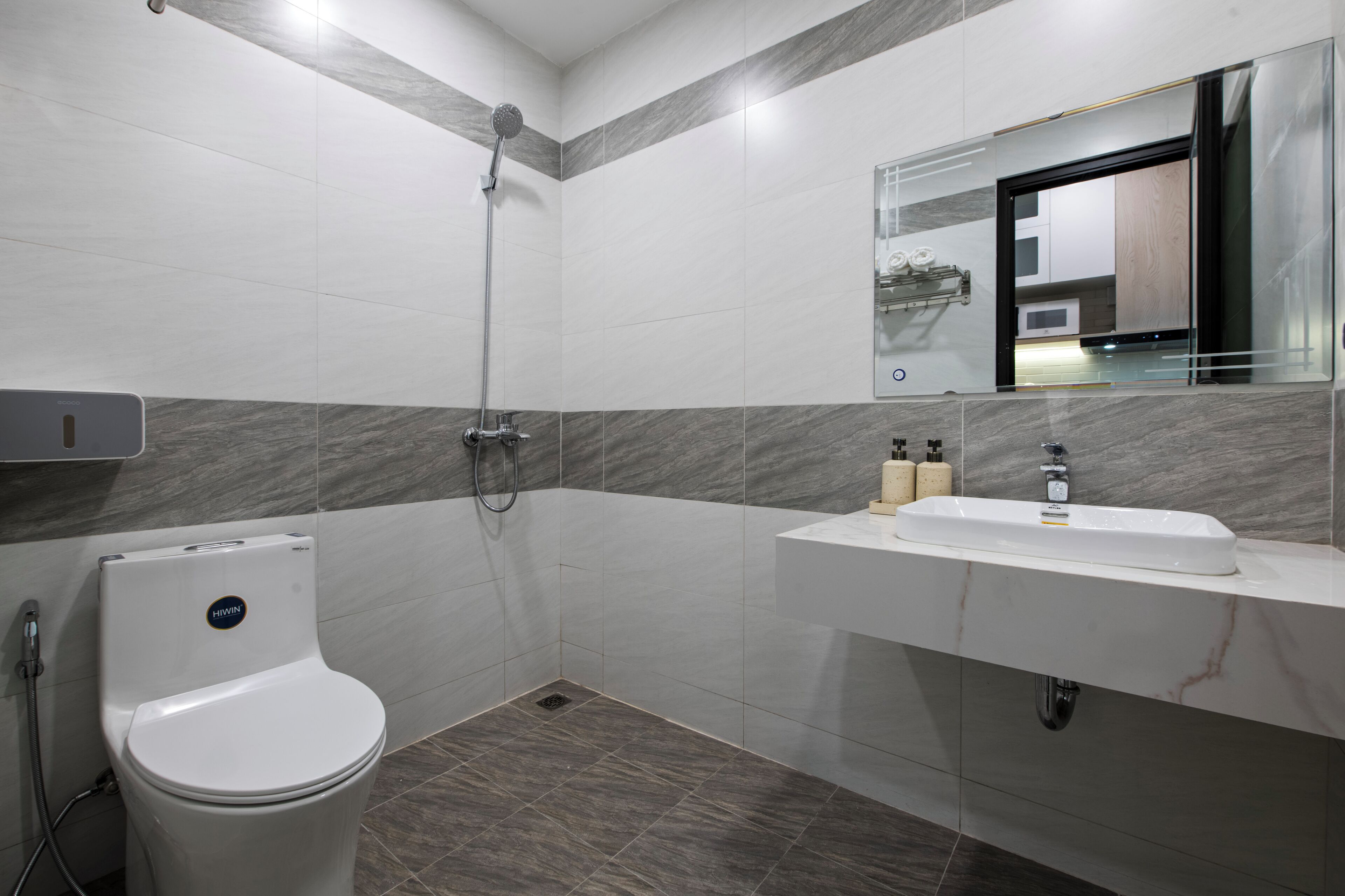 A modern bathroom with a toilet, shower, and sink.