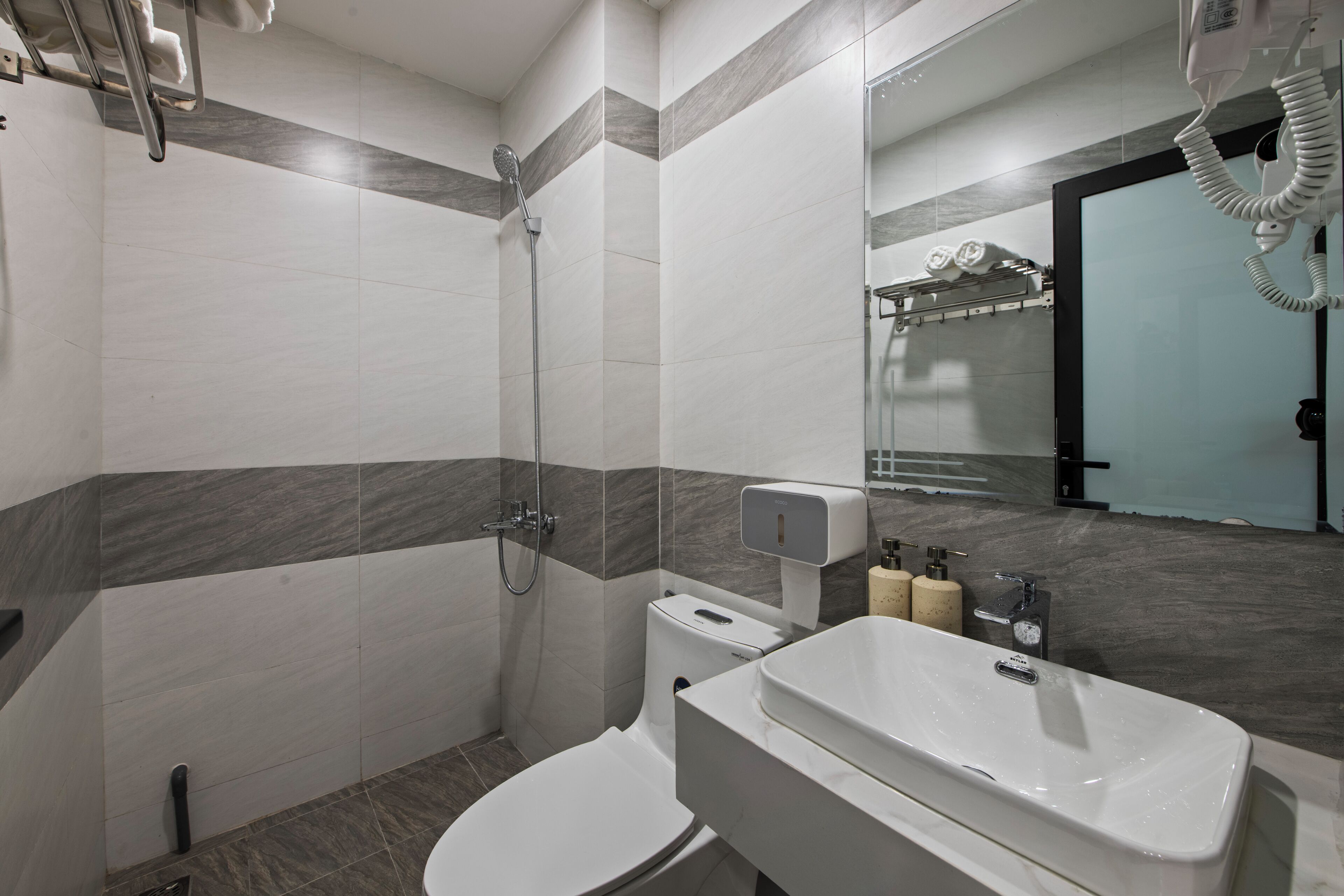A modern bathroom with a shower, toilet, and sink.